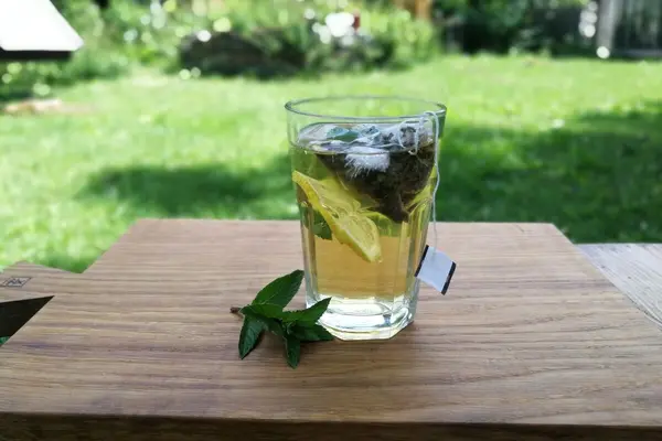 Ein Glas mit Cold Brew Tee steht auf einem Tisch im Garten.