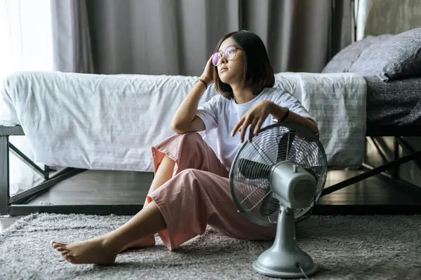 Eine Frau sitzt auf dem Boden vor einem Ventilator