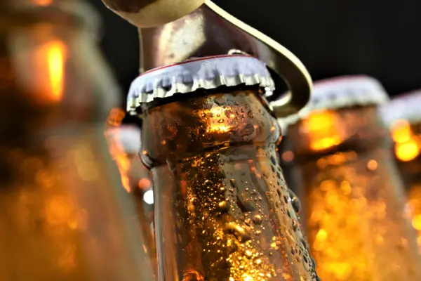Bierflaschen, deren Verschluss mit einem Bieröffner geöffnet wird, dunkler Hintergrund