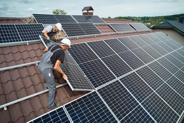 Zwei Handwerker bringen ein Solarpanel auf einem Dach an
