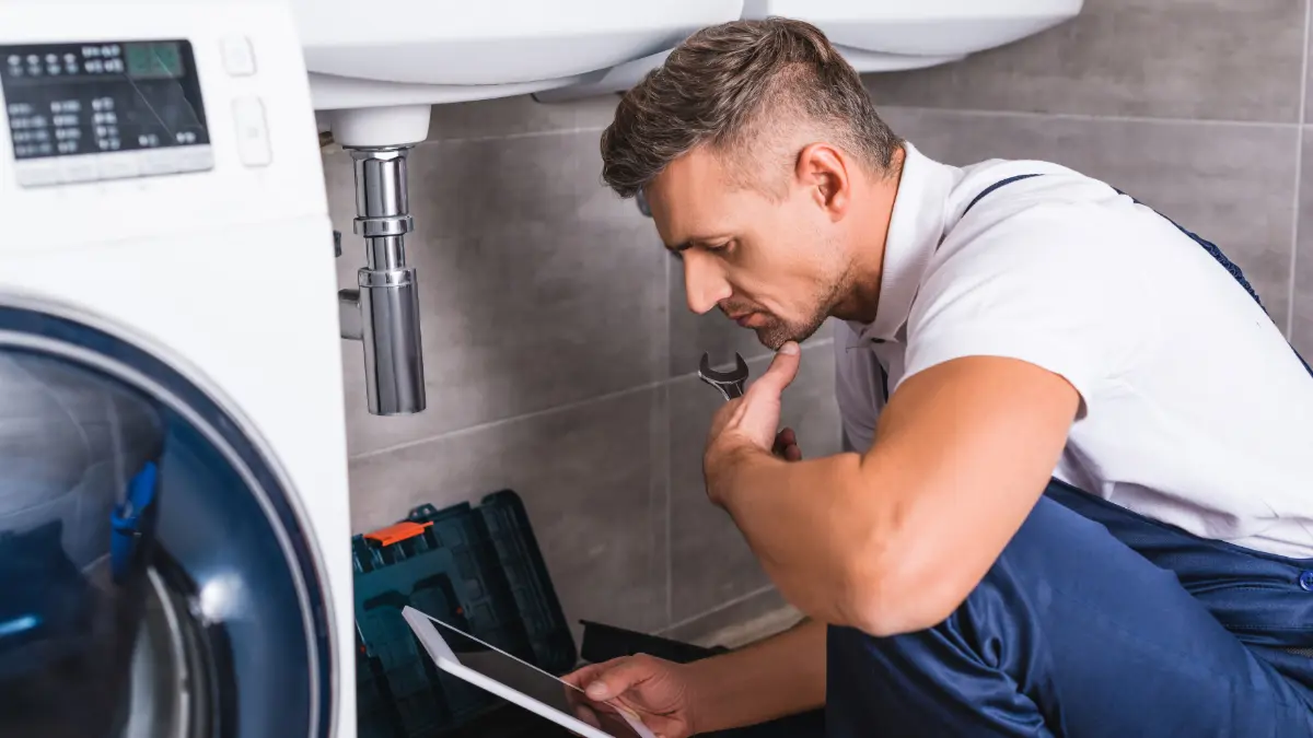 Ein Installateur kontrolliert den Wasseranschluss einer Waschmaschine
