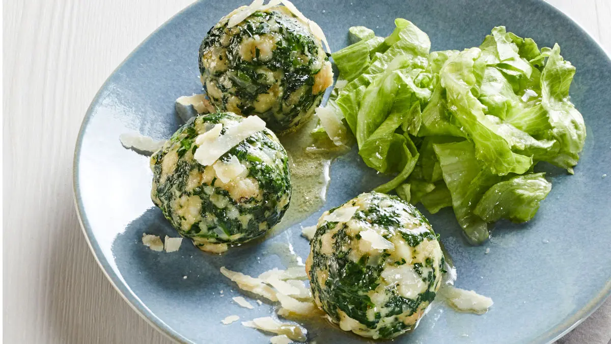Spinatknödel mit Eisbergsalat auf einem Teller