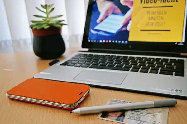 Personalausweis und Smartphone auf Schreibtisch mit Laptop