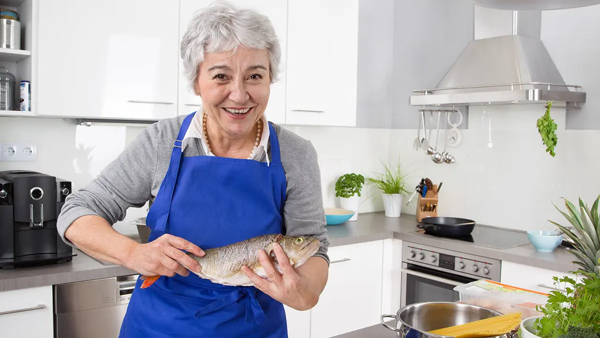 Eine Dame bereitet in der Küche Fischgericht vor