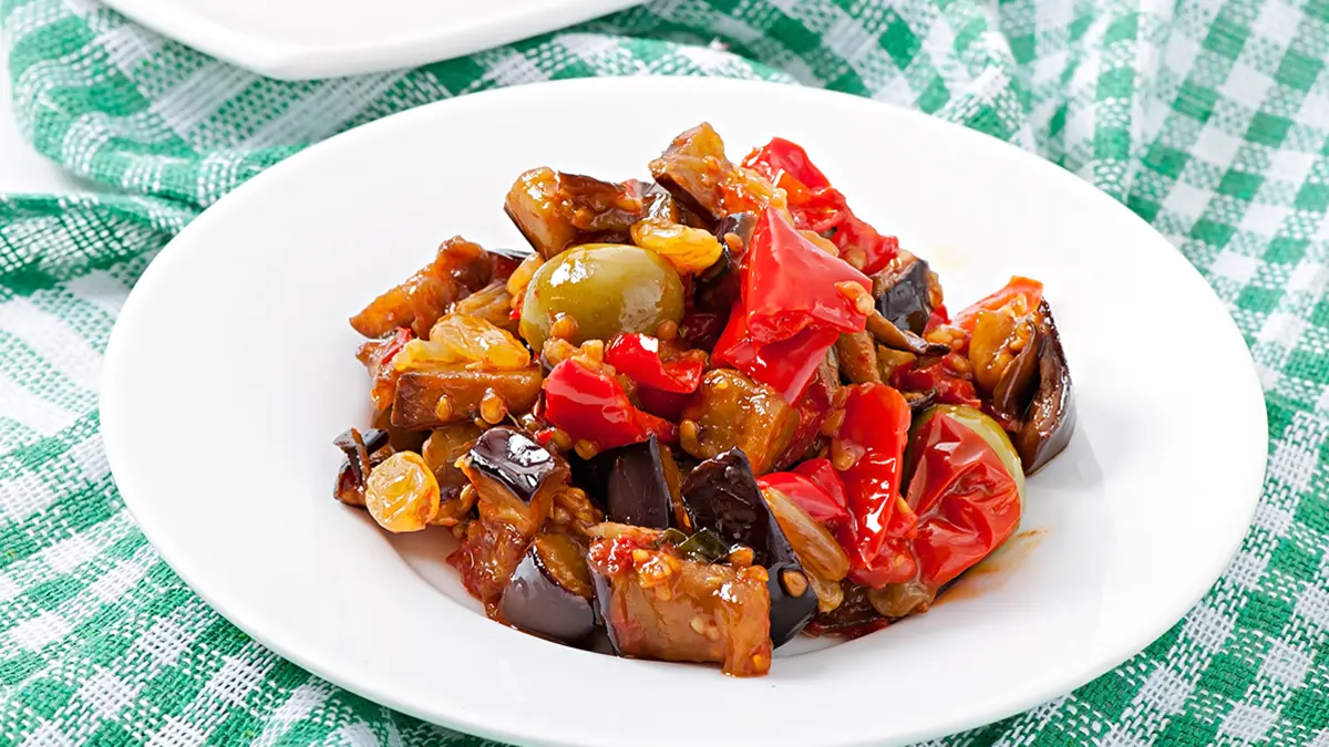 Caponata aus Aubergine, Paprika und Oliven auf einem Teller