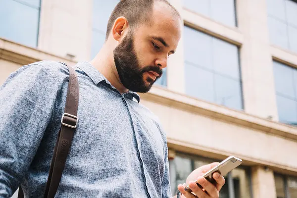 Ein Mann schaut irritiert auf das Display seines Smartphones