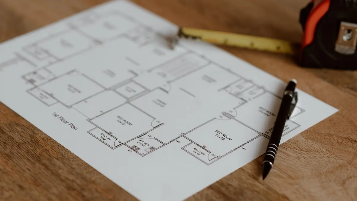 Grundriss auf Papier, Maßband und Stift liegen auf dem Tisch