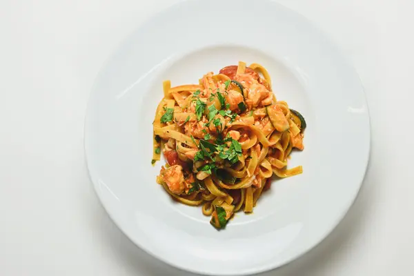 Nudeln mit Zucchini Tomatensauce auf einem weißen Teller