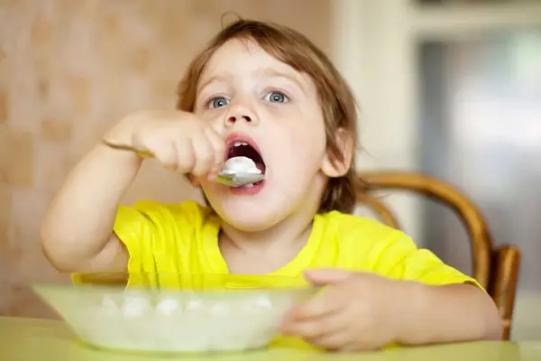 Ein Kind ist mit einem Löffel Quark aus einem teller