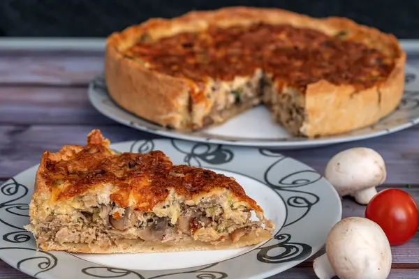 Ein Stück aus einer Quiche mit Zutaten daneben