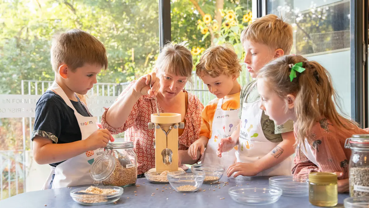 Ernährungsbildungsaktion mit einer Gruppe von Kindern mit einer Flockenquetsche.