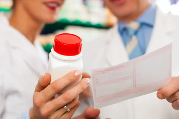 Eine Frau hält eine Pillendose, ein Mann ein Rezept in die Kamera