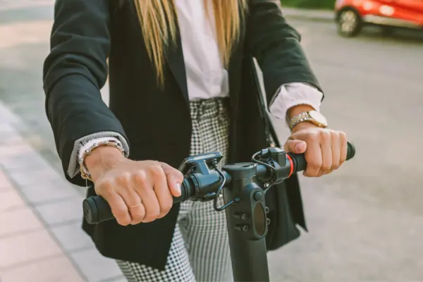 eine junge Frau fährt mit einem E-Scooter über einen Gehweg