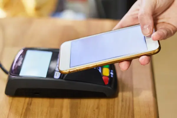 Ein Smartphone wird zur Bezahlung an eine Kartenlesegerät gehalten