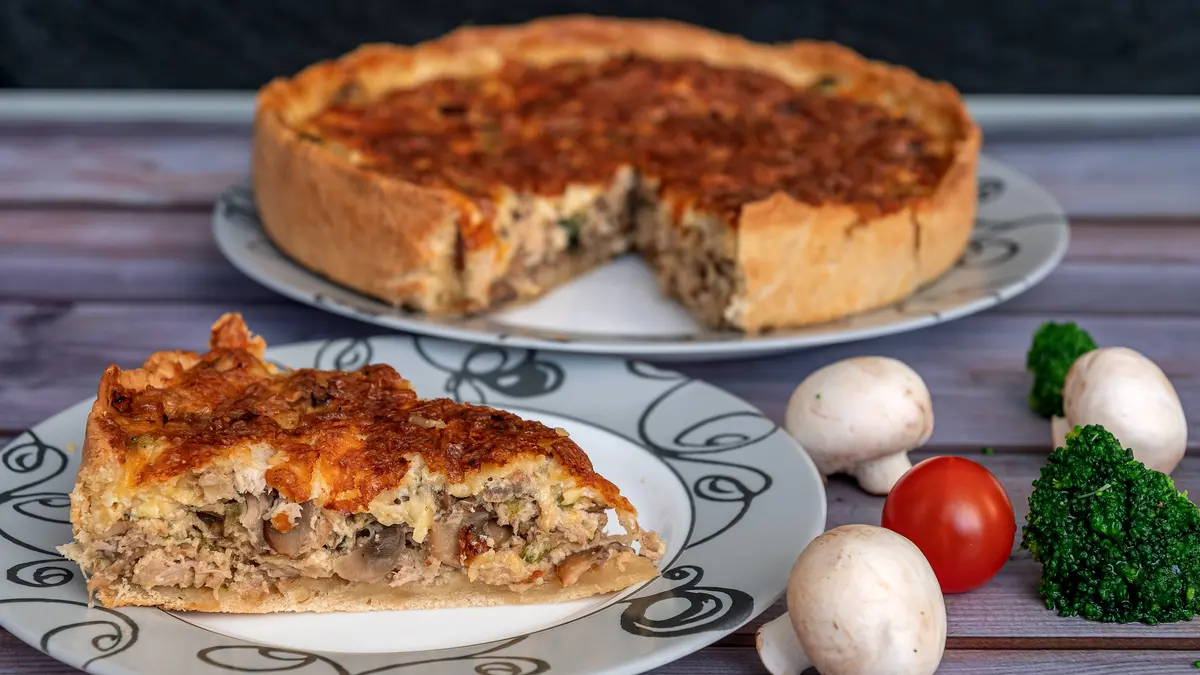 Ein Stück aus einer Quiche mit Zutaten daneben