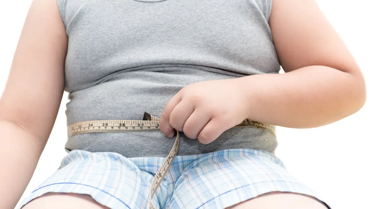 Bauch eines übergewichtigen Jungen mit Maßband.