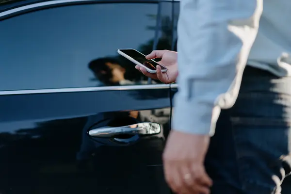 Mann beim Öffnen der Tür eines Autos mit seinem Smartphone