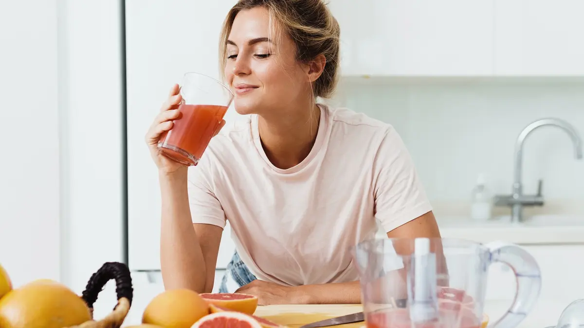 Eine Frau trinkt ein Glas Grapefruitsaft.