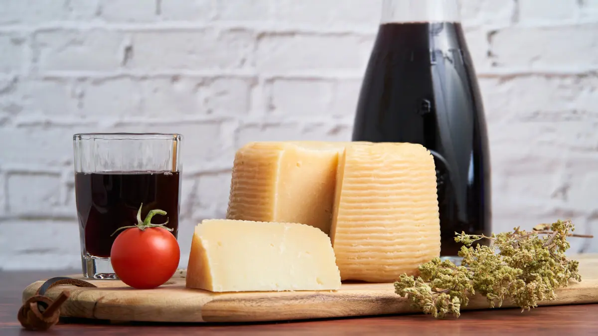 Auf einem Tisch stehen mehrere Lebensmittel, die Histamine enthalten - unter anderem Käse und eine Tomate.