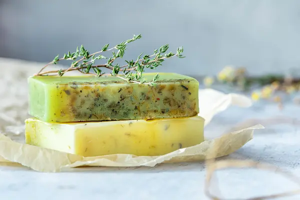 Zwei Stück selbstgemachte Seife mit einem Kräuterzweig dekoriert 