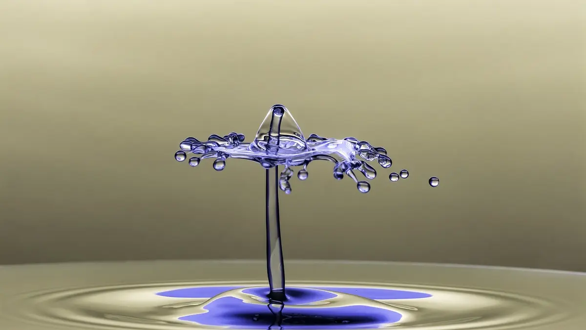 Aufnahme eines farbigen Tropfens, der auf klares Wasser trifft