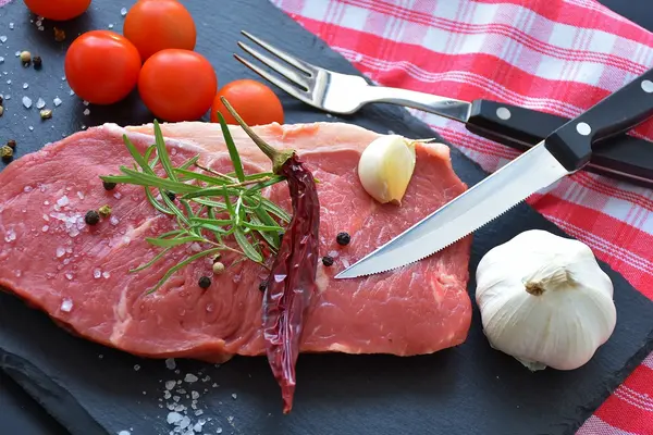 Rohes Steak mit Gewürzen, Knoblauch und Tomaten dekoriert