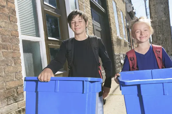 Kinder mit blauen Recyclingtonnen