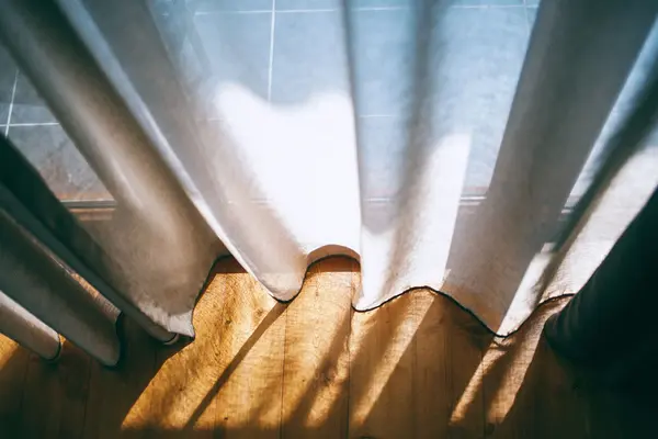 Fenster, Vorhänge und Boden im Sonnenlicht