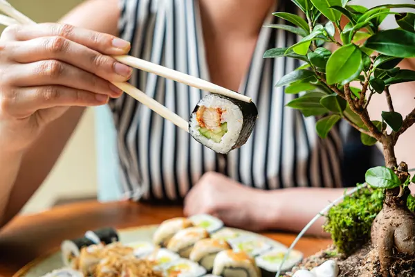 Eine Person isst Sushi mit Stäbchen