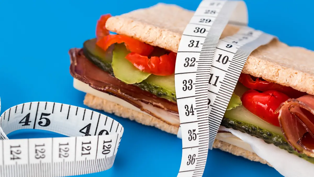 Dick belegtes Sandwich, von einem Maßband umwickelt