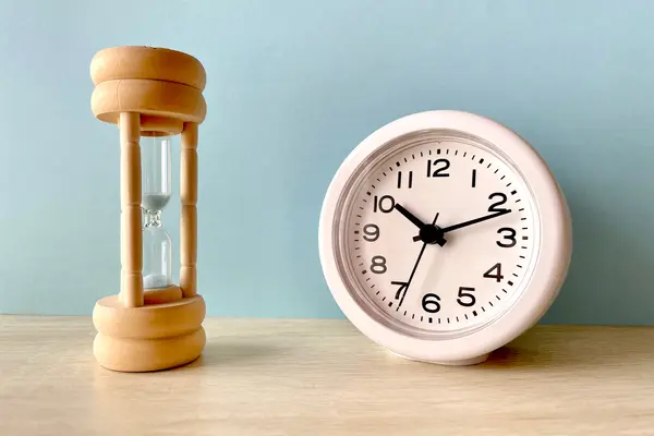 Sanduhr steht neben einer Uhr