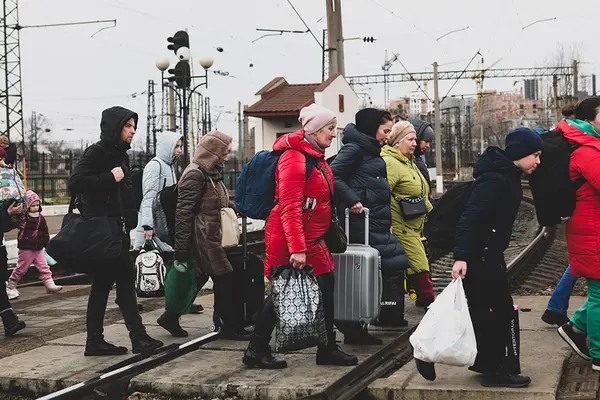 Eine Gruppe von Menschen in der Ukraine läuft mit Taschen über einen Gleisabschnitt