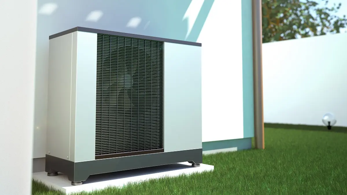 Eine Wärmepumpe an der aüßeren Hauswand im Garten