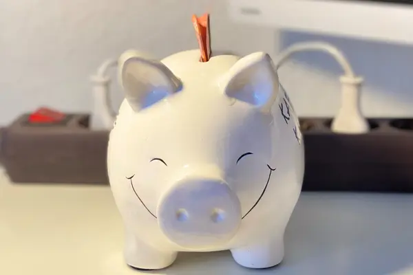 Sparschwein mit einer steckdose im Hintergrund