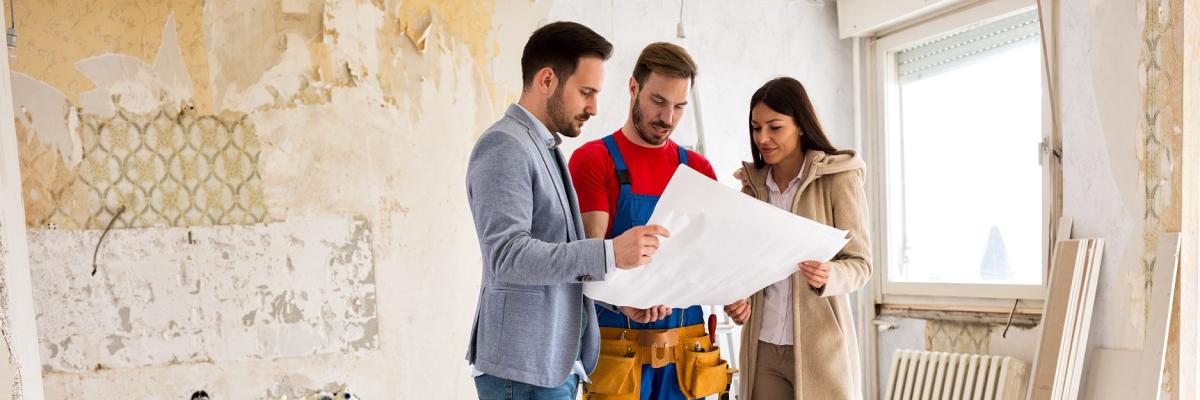 Drei Menschen schauen auf einen Bauplan.