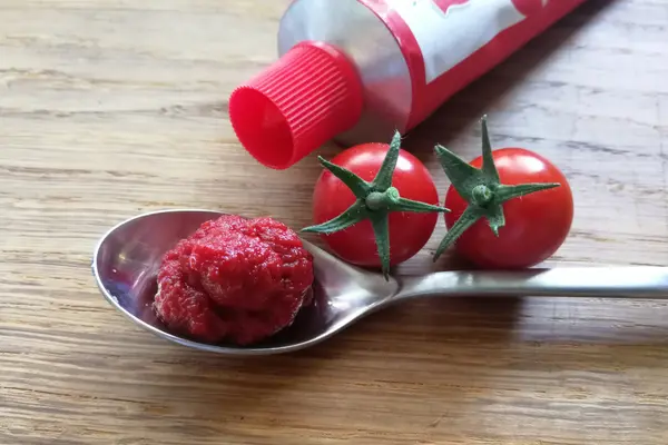 Ein Löffel Tomatenmark mit einer Tube und zwei Tomaten