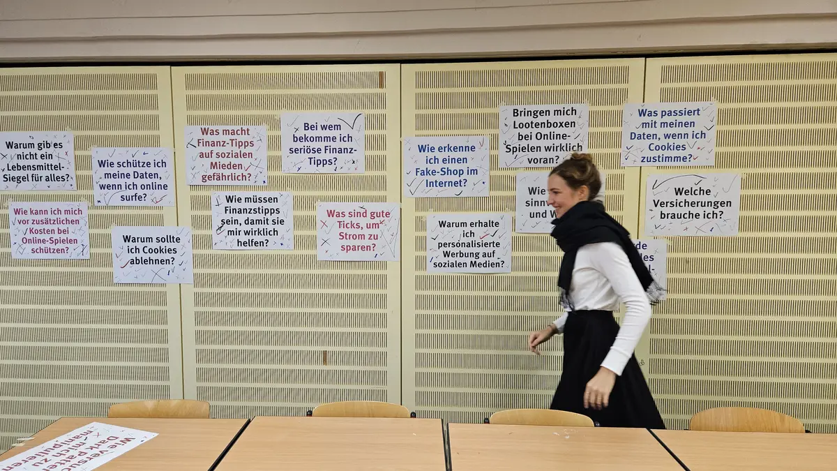 Eine june Frau geht an einer Pinwand vorbei, an der viele Zettel angepinnt sind
