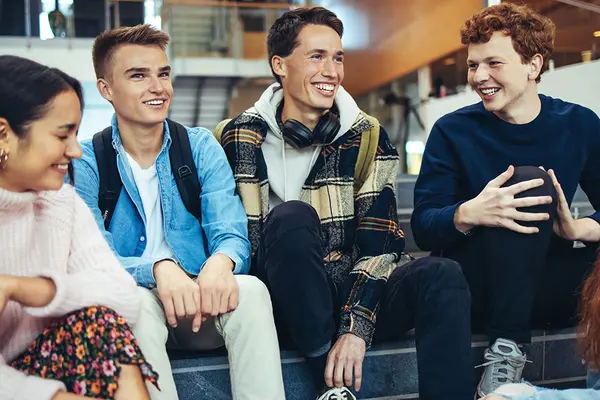 Eine Gruppe Jugendlicher sitzt auf einer Treppe in einer Schule