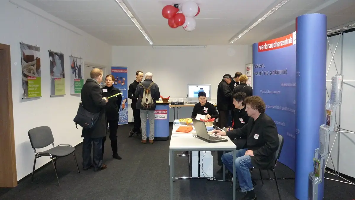 Ein Infostand in einem Raum und Besucher.