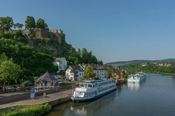 Ein Passagierschiff legt unterhalb einer Burg an.