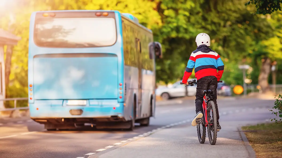 Kind fährt auf Fahrrad hinter einem Bus her