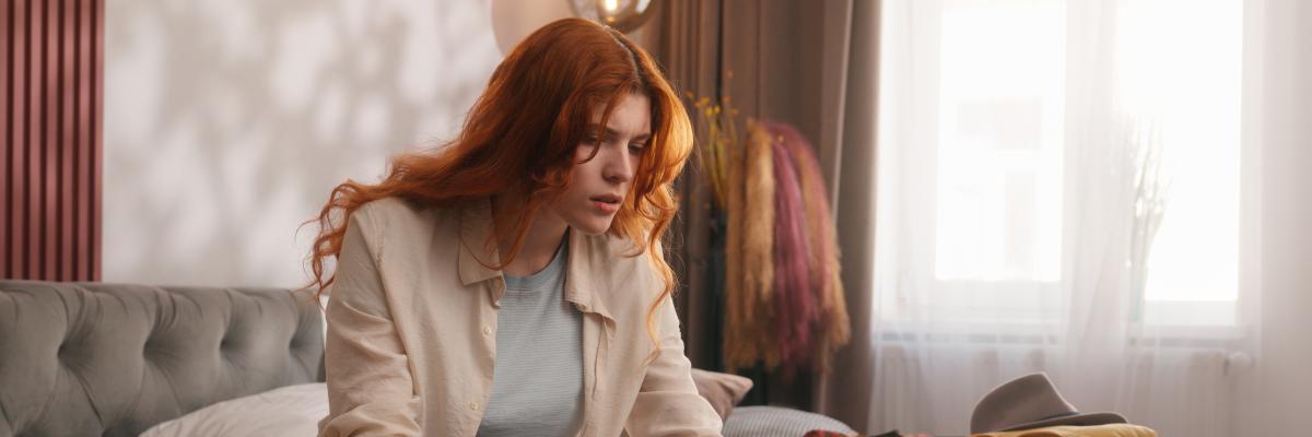 Schmuckbild: Frau, die gestresst auf Laptopbildschirm schaut und Reisepass und Flugtickets in der Hand hält.