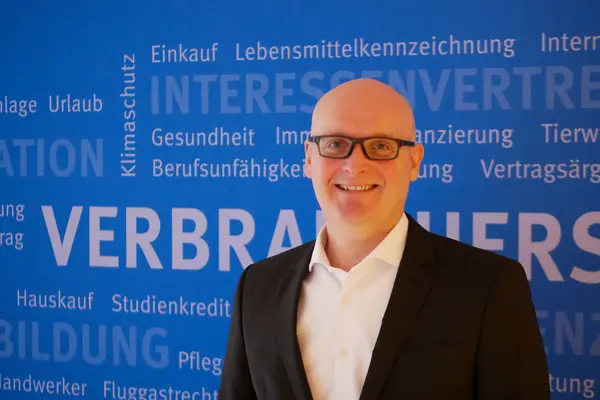 Stefan Bock, Vorstand der VZSH, Porträt vor blauer Wand
