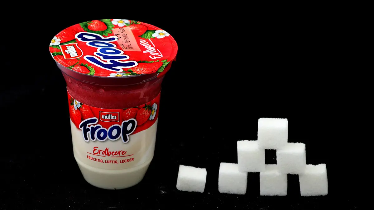 Joghurtbecher von Müller Froop und daneben eine Zuckerwürfel-Pyramide
