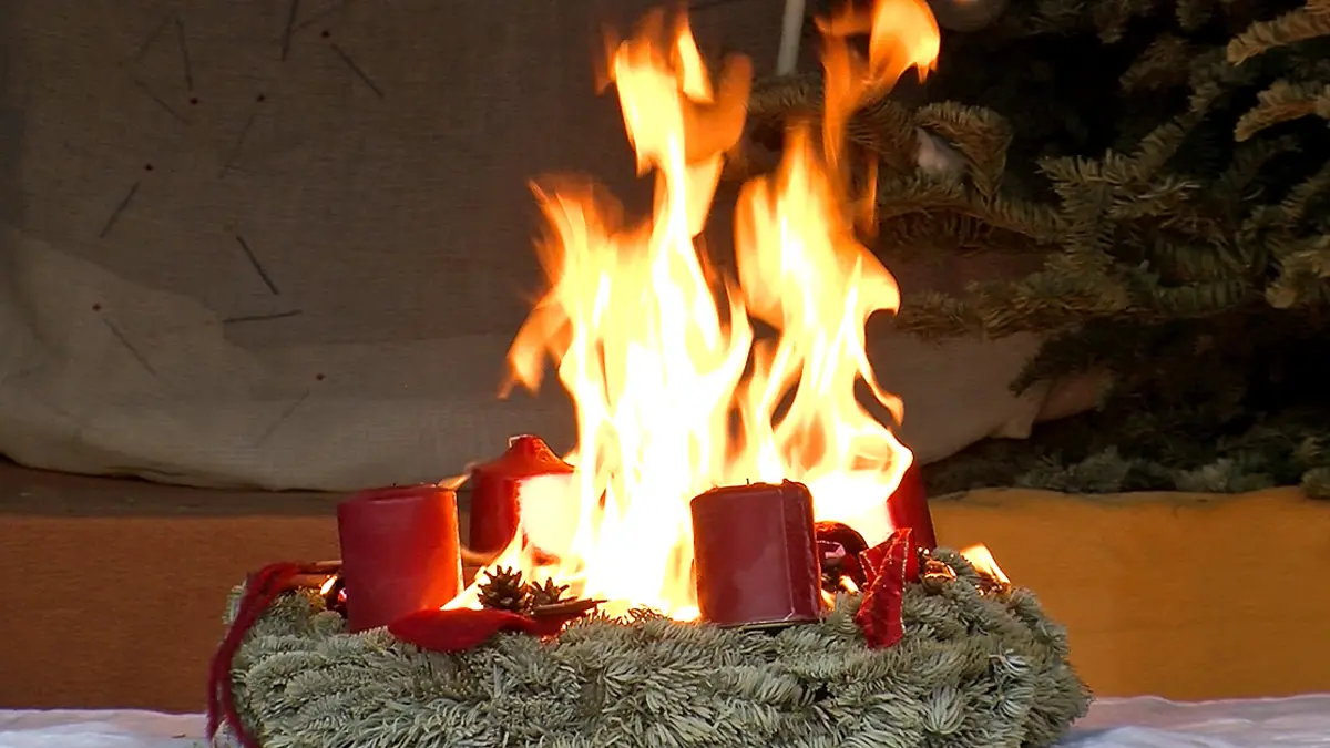 Flammen schlagen aus der Mitte eines Adventskranzes in die Höhe.