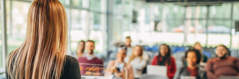Eine Studentin hält einen Vortrag vor einer Gruppe Studierender.