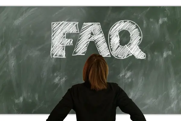 Eine Frau steht vor einer Tafel, auf der mit Kreide "FAQ" geschrieben wurde.