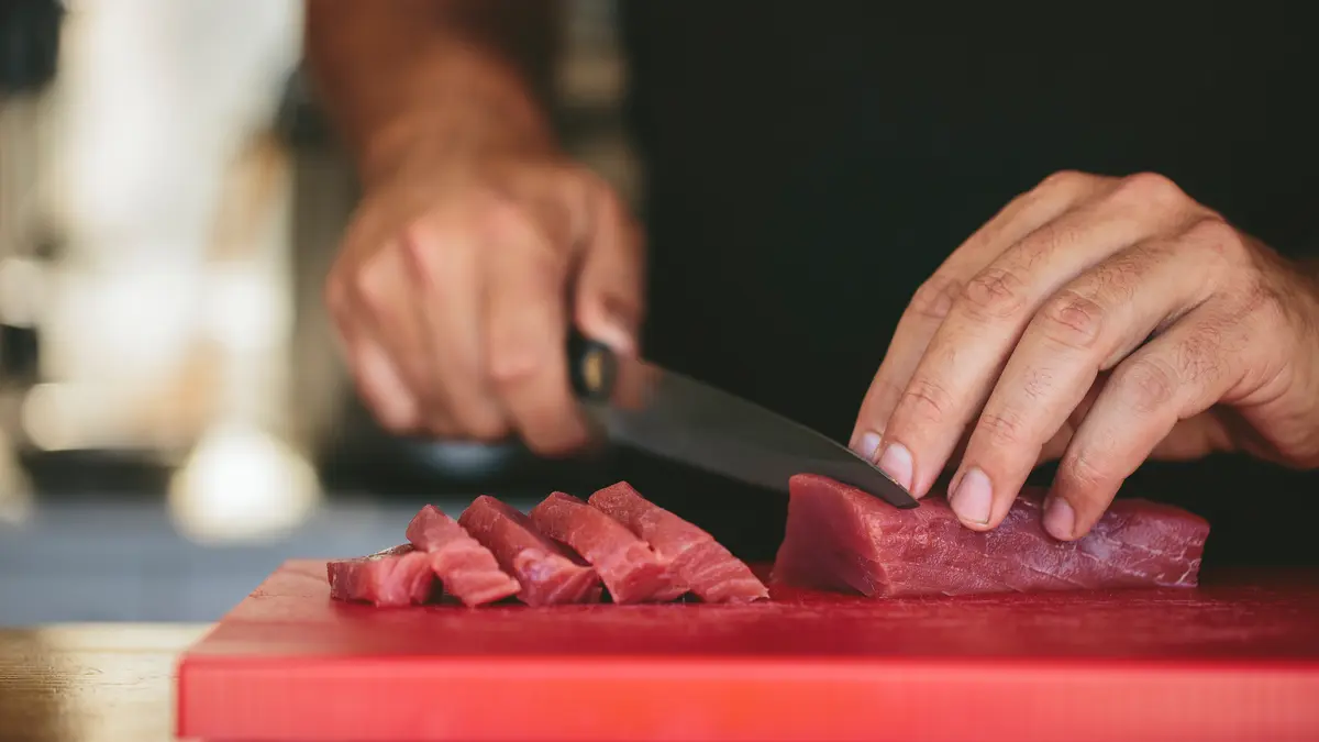 Hände schneiden Fleisch auf Küchenbrett