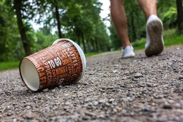 Ein weggeworfener To-go-Becher liegt auf dem Weg