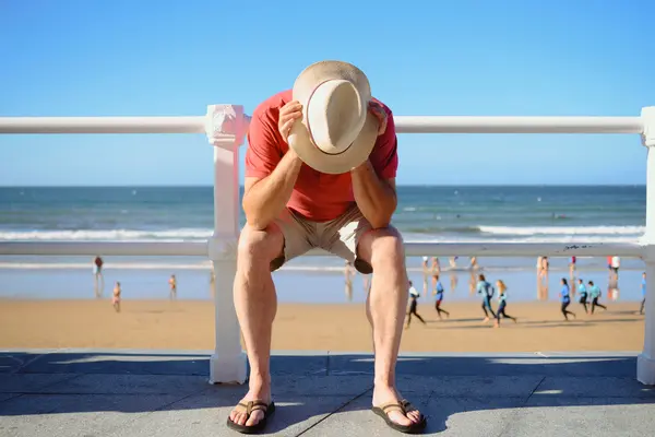 Mann stützt sich den Kopf auf die Hände am Strand